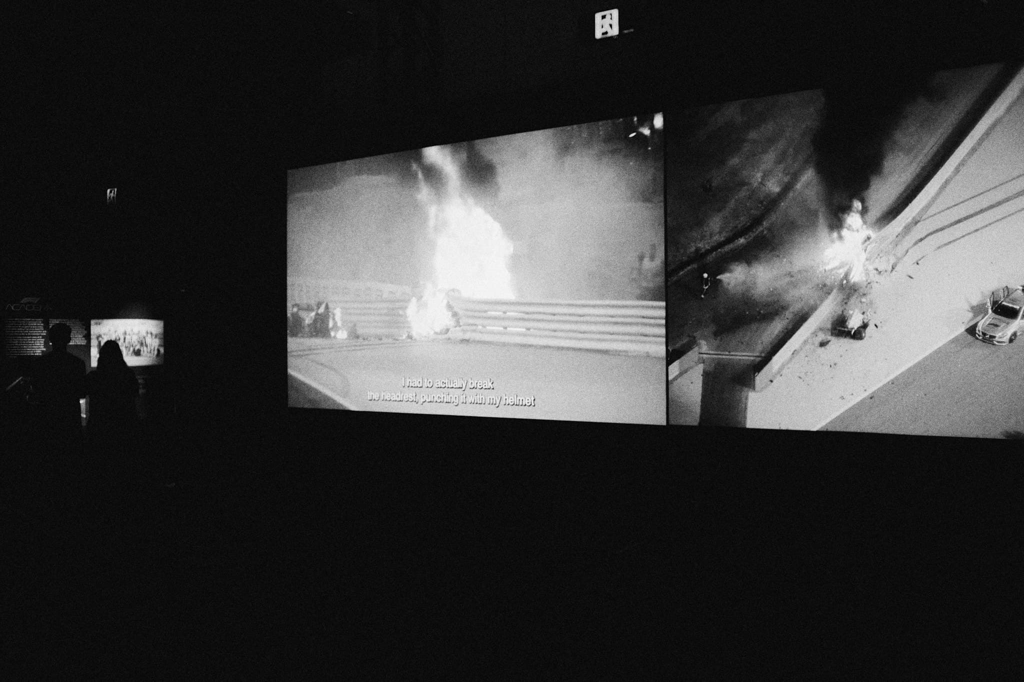 Silhouettes watching Grosjean crash footage at exhibition