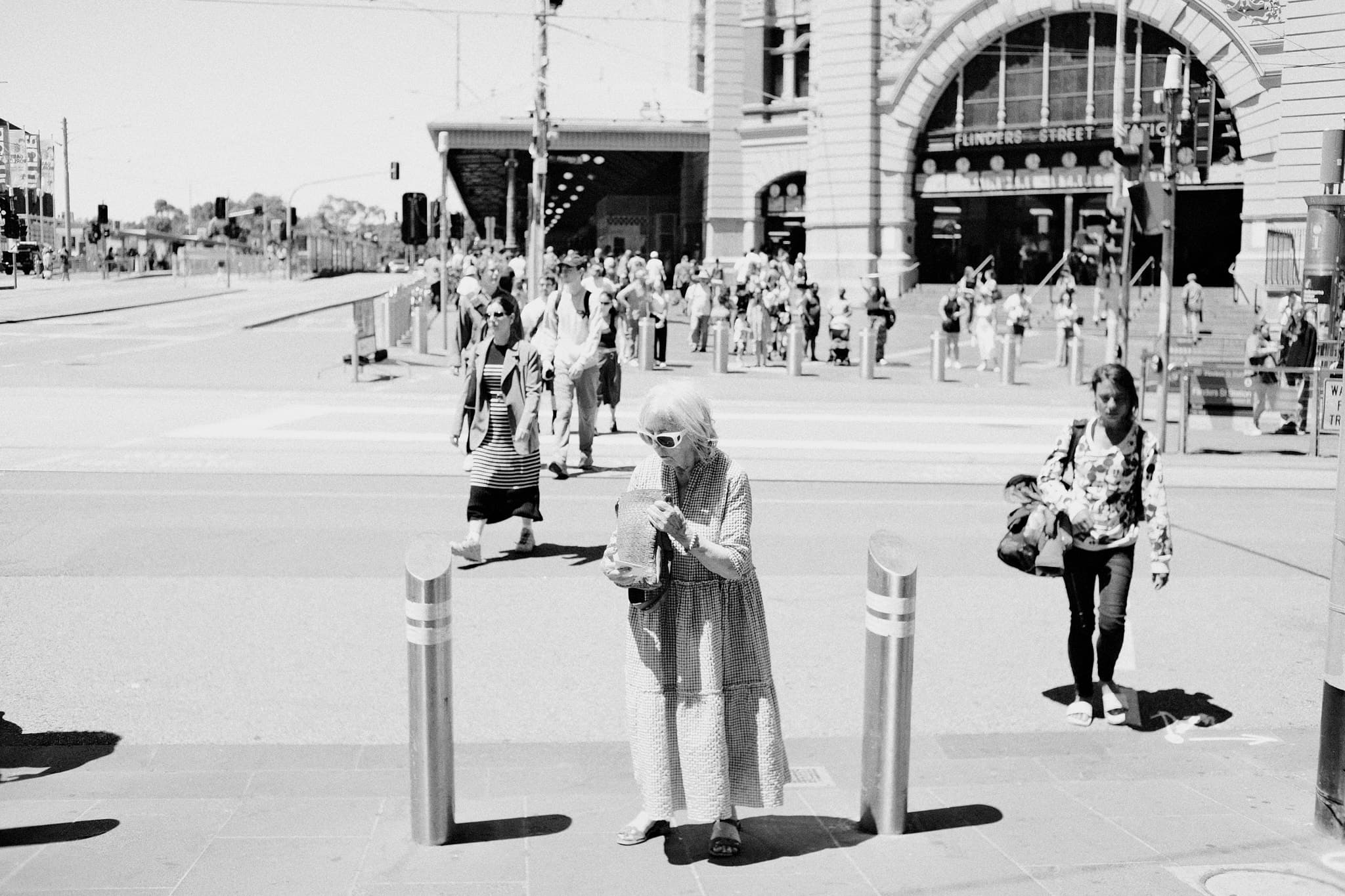 Woman alone between bollards, Flinders Street behind